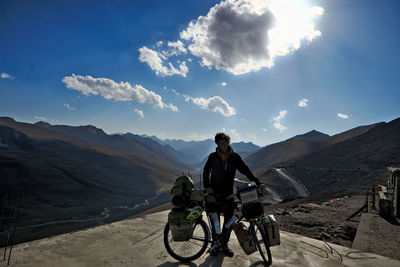 Man riding bicycle on mountain against sky