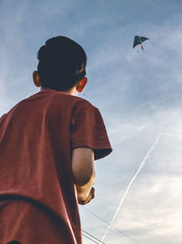 Side view of boy standing against sky