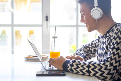 Smiling teenage boy talking on video call at laptop