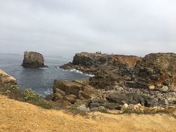 Scenic view of rocks on sea against sky