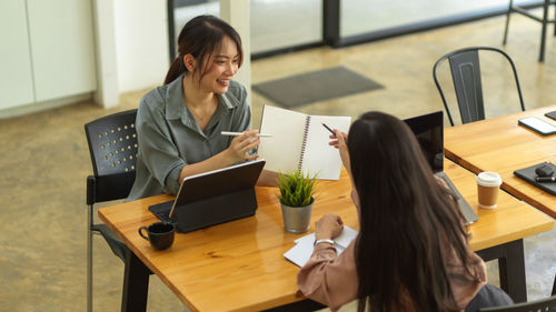 Businesswomen discussing over book in office