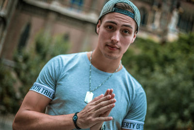 Portrait of young man holding camera outdoors