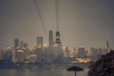 Overhead cable car against illuminated cityscape at night
