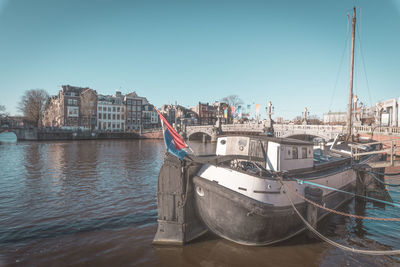 Boats moored at harbor against clear sky