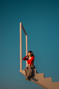 Full length of woman standing against blue wall