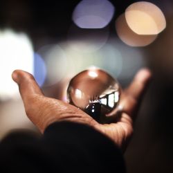 Person hand holding reflection of restaurant in glass sphere