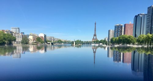 Reflection of buildings in lake against blue sky