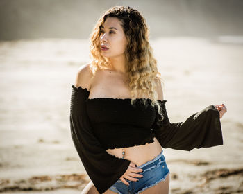 Portrait of beautiful young woman standing at beach