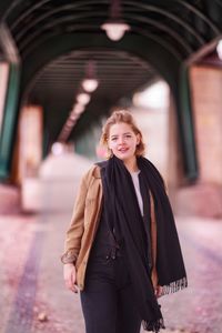 Portrait of smiling young woman standing against built structure