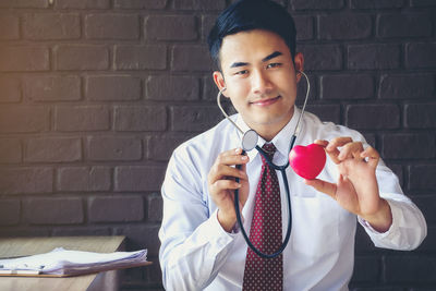 Portrait of smiling doctor holding model heart and stethoscope