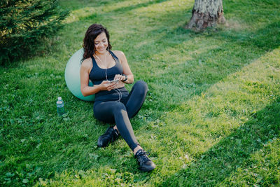High angle view of woman using smart phone while sitting on land