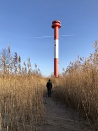 Man standing on field against lighthouse 