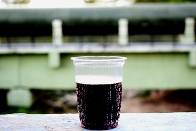 Close-up of drink in glass on retaining wall
