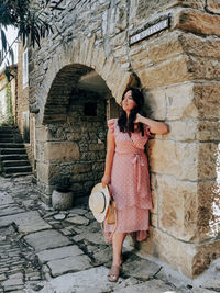 Full length of woman standing against wall