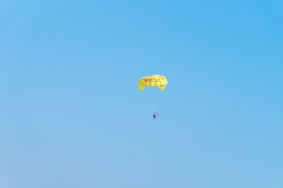 Distance view of people paragliding against clear sky