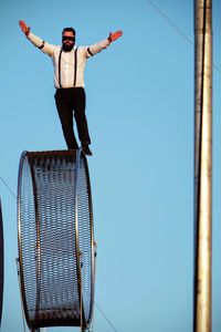 Low angle view of young man standing against sky