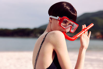 Portrait of young woman wearing sunglasses while standing at beach