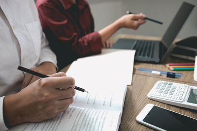 Midsection of man using mobile phone on table