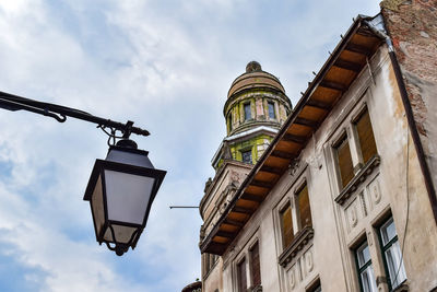 Low angle view of street light by building against sky