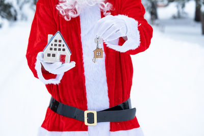 Rear view of woman holding gift while standing on snow