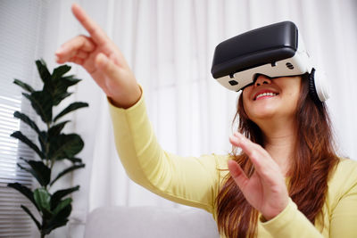 Young asian woman wearing virtual reality glasses, hand touching the air. vr headset. vr concept.