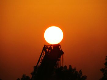 Low angle view of silhouette trees against orange sky