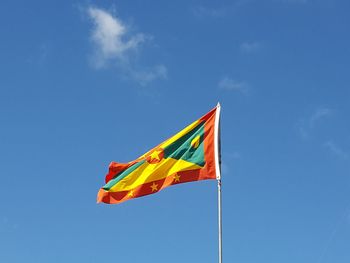 Low angle view of grenadan flag against blue sky