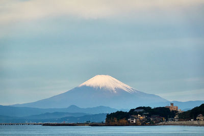 Scenic view of sea and snowcapped mountain against cloudy sky in the morning