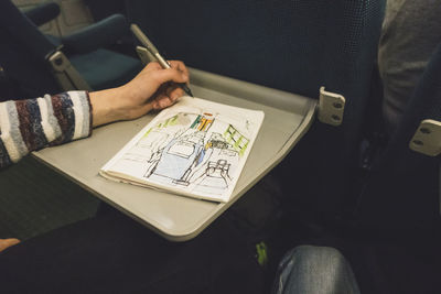 Hand of girl drawing in train