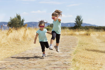 Full length of children on dirt road against sky