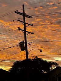 Low angle view of silhouette electricity pylon against sky during sunset