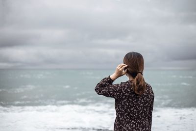 Rear view of woman standing against sea