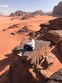 High angle view of man sitting on rock against sky