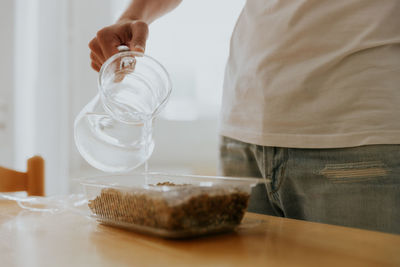 A young man waters wheat seeds into a container.