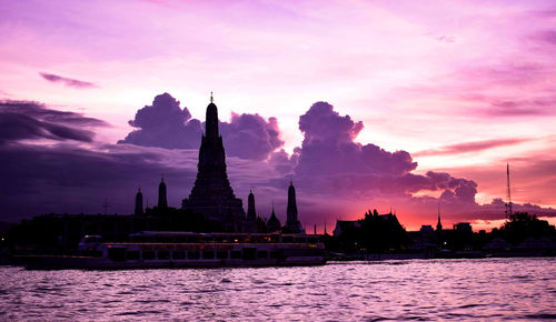 Temple by building against sky during sunset