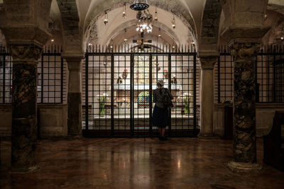 Rear view of woman standing by fence in church