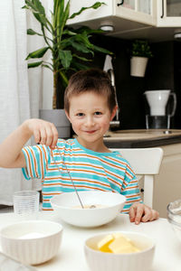 A little boy kneads the dough with a whisk and tastes it. the children are baking a cake. 