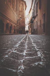 Rear view of person walking on street amidst buildings