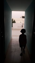 Rear view of boy standing at entrance of building