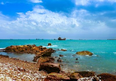 Rock formations on coast against cloudy sky