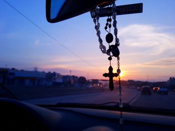 Rosary hanging in car during sunset