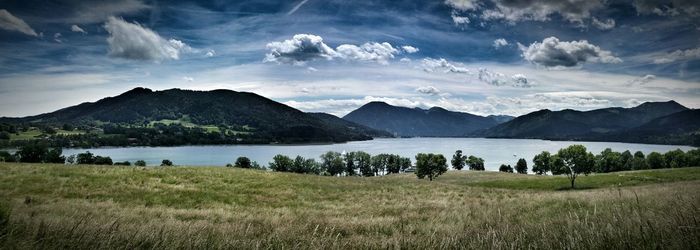 Lake with mountain range in background against cloudy sky