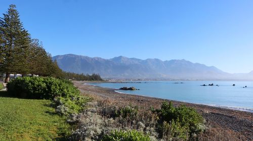 Scenic view of sea and mountains against clear blue sky