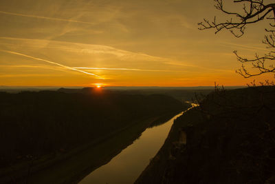 Scenic view of silhouette vapor trail against sky during sunset