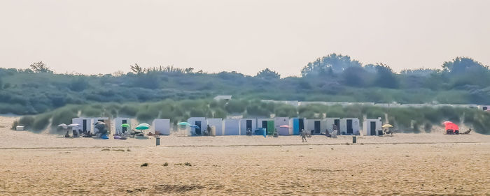 Hooded chairs on beach against clear sky