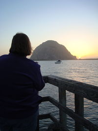 Rear view of man looking at sea against sky