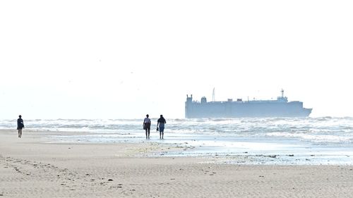 People on beach against clear sky