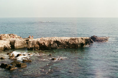 Scenic view of rocks in sea against clear sky