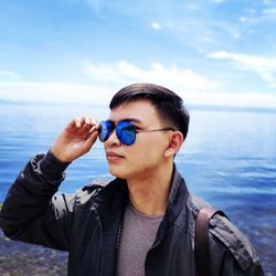 Portrait of young man wearing sunglasses against sea