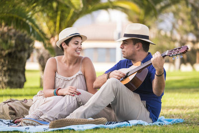 Happy couple sitting on picnic blanket at park